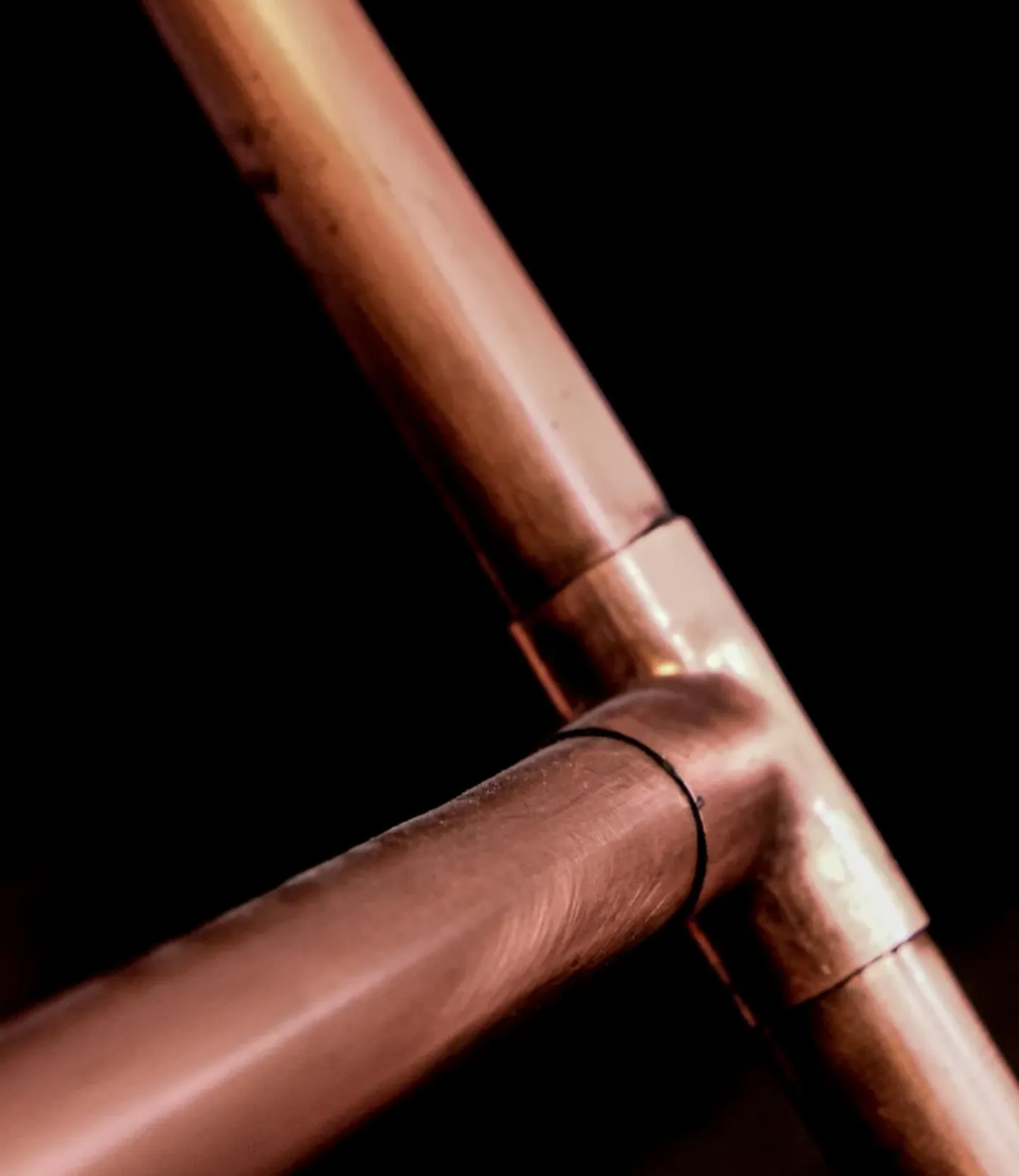 Plumber examining corroded pipes under a Rocklin kitchen sink, flashlight illuminating green and white mineral buildup.