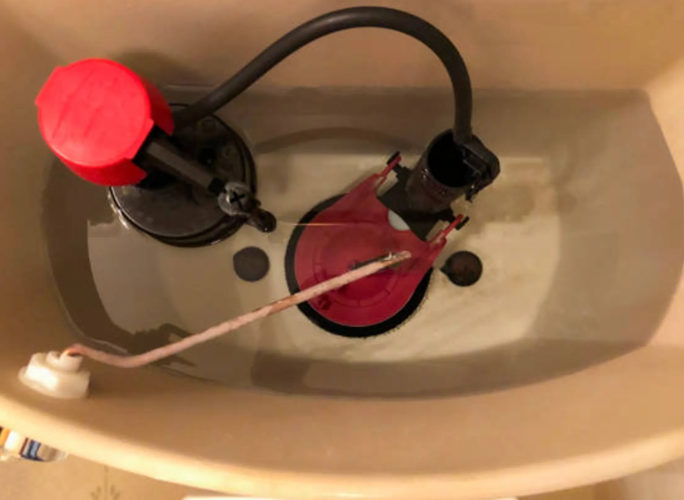 Homeowner leaning near a toilet tank, listening closely with the lid off.