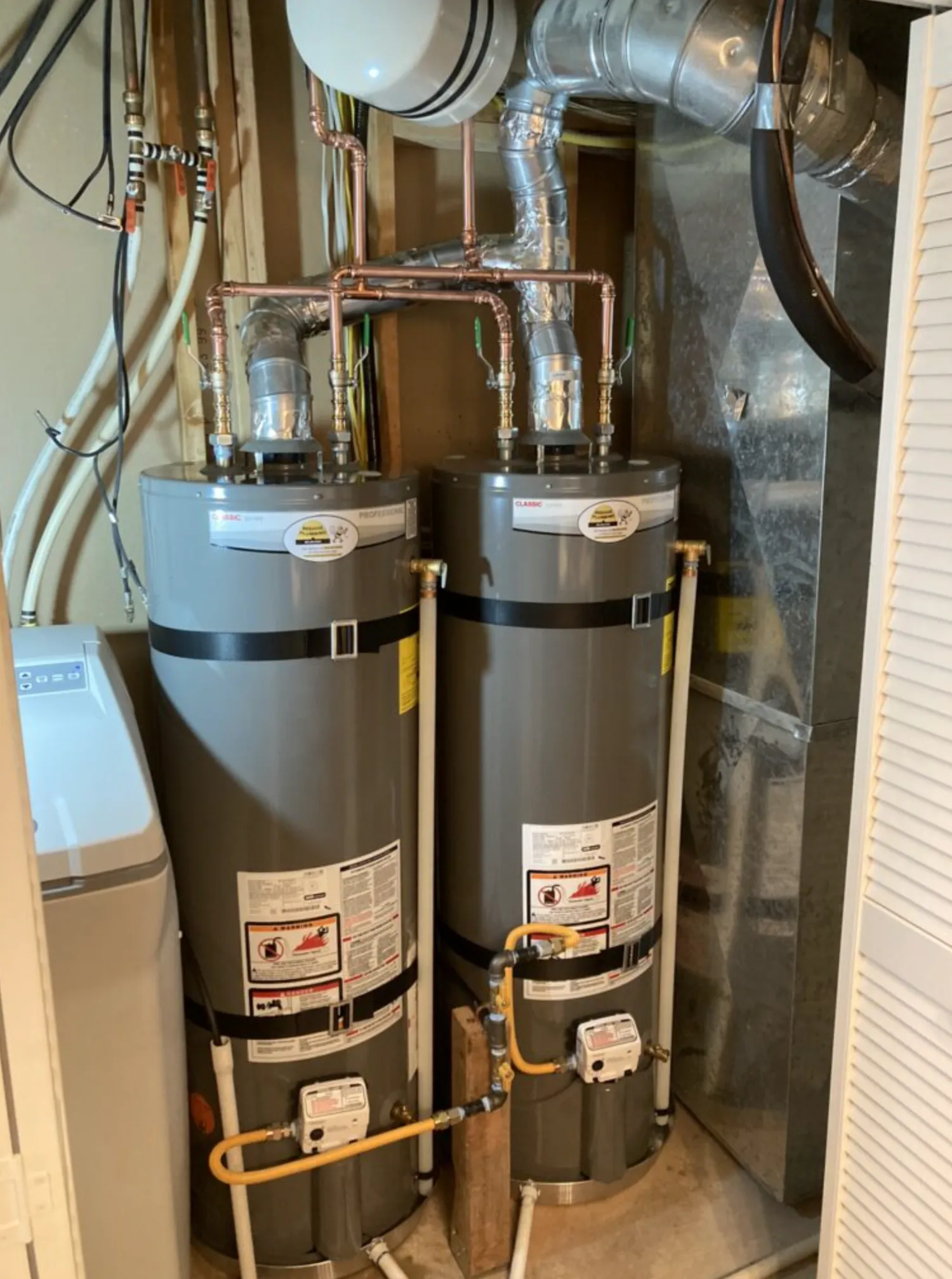 Sacramento homeowner in a bright garage utility area looking at a tank-style water heater, morning light coming in through the open garage door.