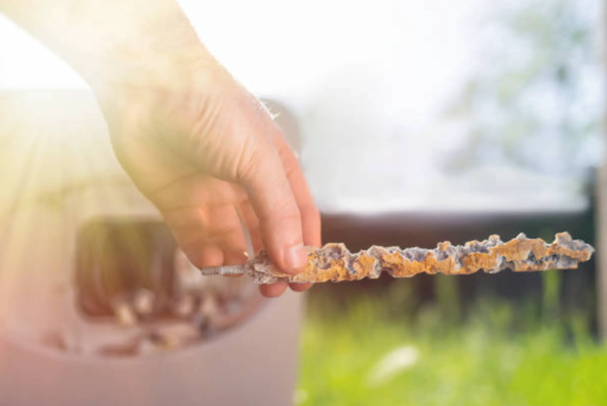 Close-up of a corroded, partially dissolved anode rod and a new replacement rod side by side on a workbench.